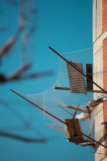 A construction site with visible safety netting and debris against a clear blue sky.