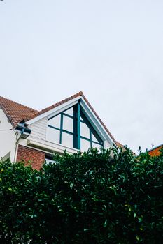 A picturesque view of a brick house with a gabled roof surrounded by lush greenery.
