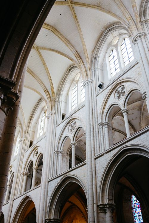 Free Low angle view of majestic Gothic cathedral interior with ornate columns and arched windows. Stock Photo