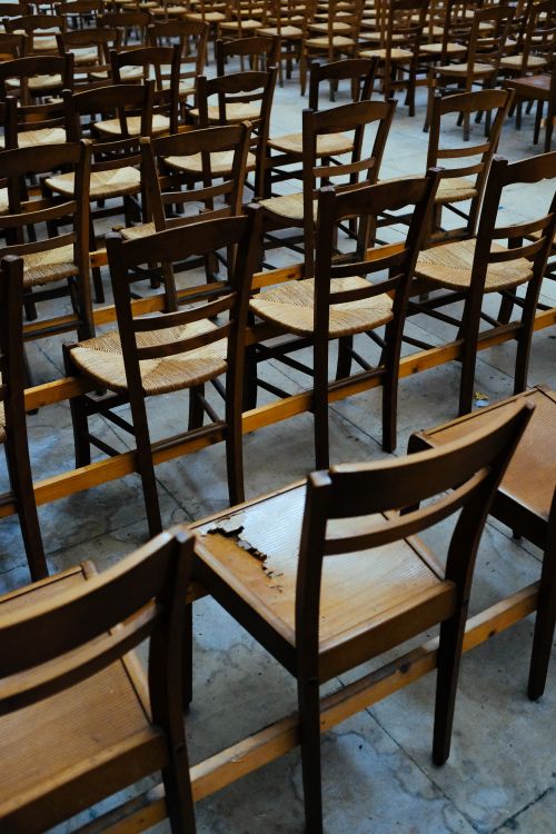 Free Arrangement of empty wooden chairs aligned in rows, creating symmetry in an indoor setting. Stock Photo