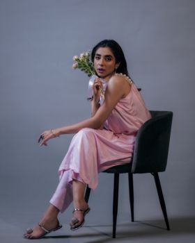 Stylish woman in a pink dress sitting with flowers in a studio shoot.