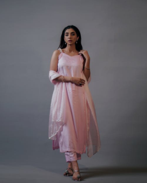 A Beautiful Woman in Pink Dress Standing Near Gray Wall while Posing at the Camera