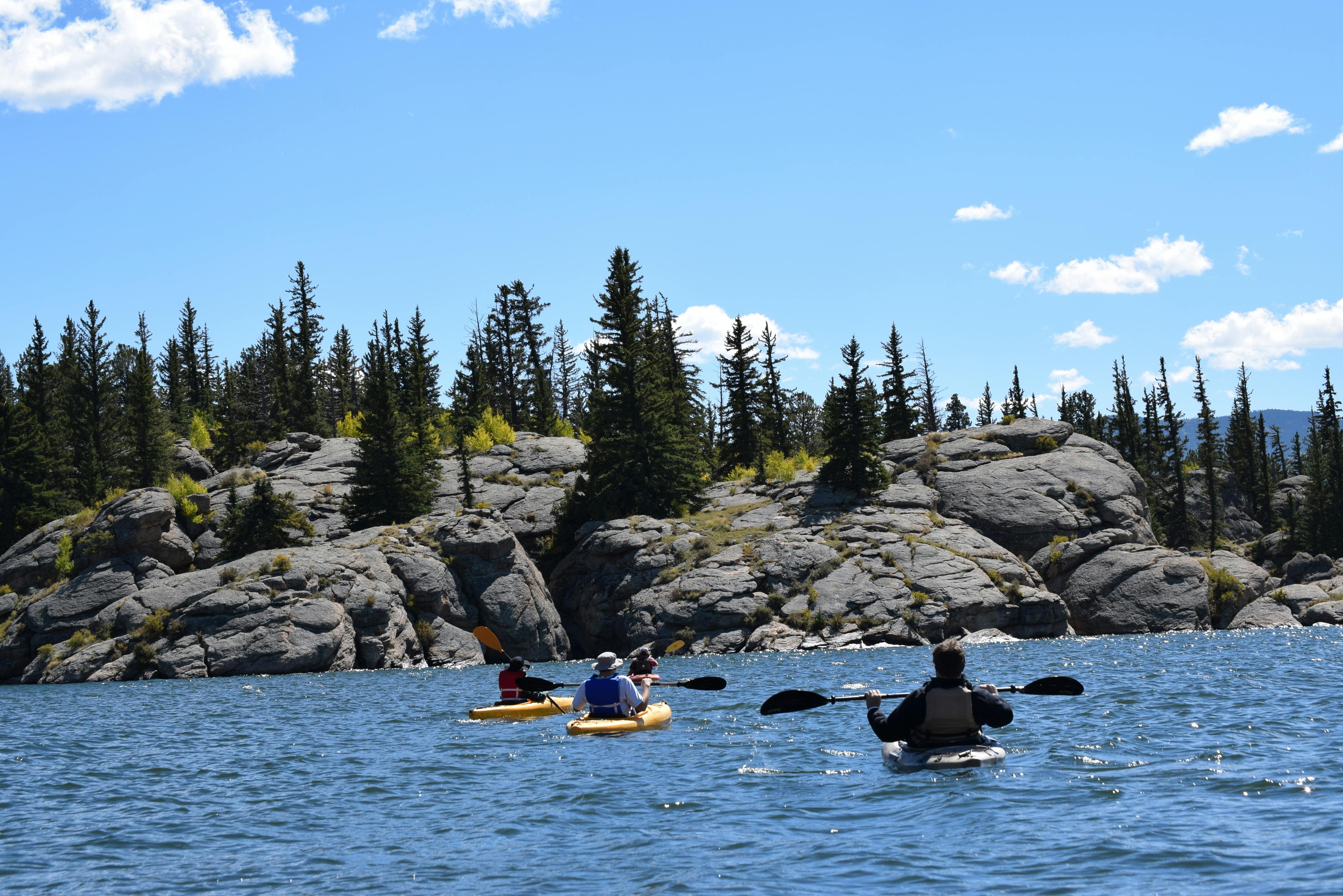 Kayaker paddling through cold water fjord with mountains in background