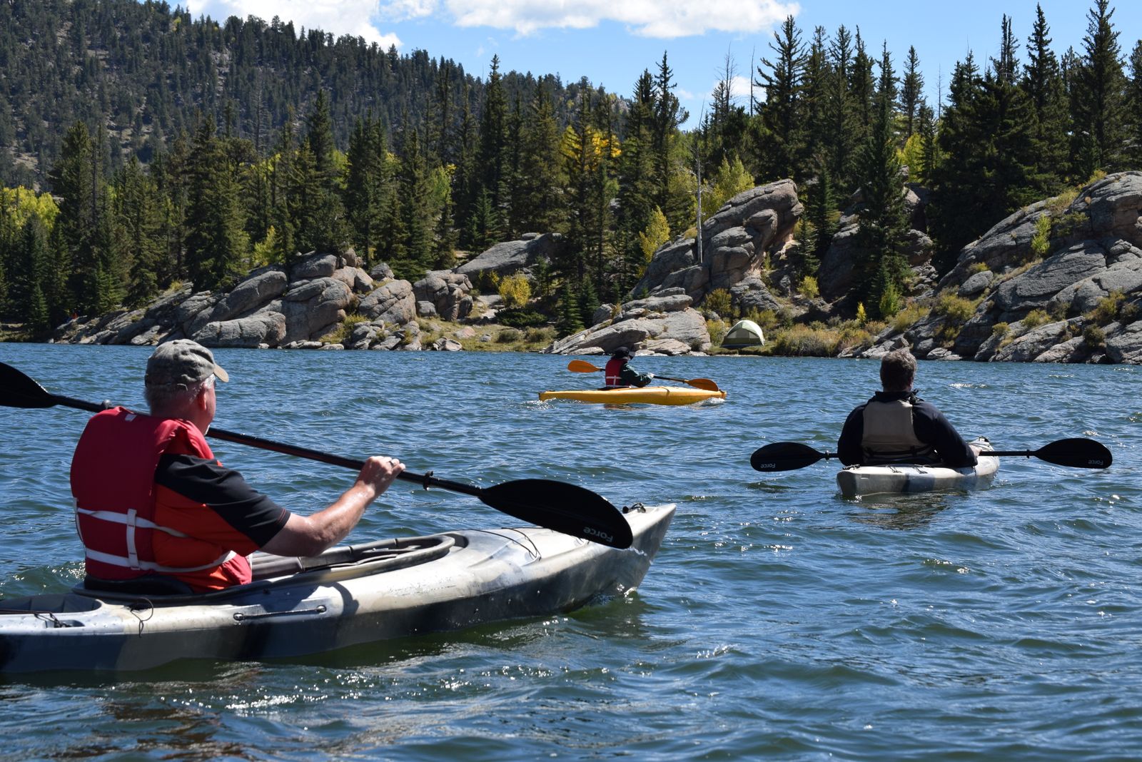 Three kayakers paddling together on crystal clear tropical water on an ocean adventure