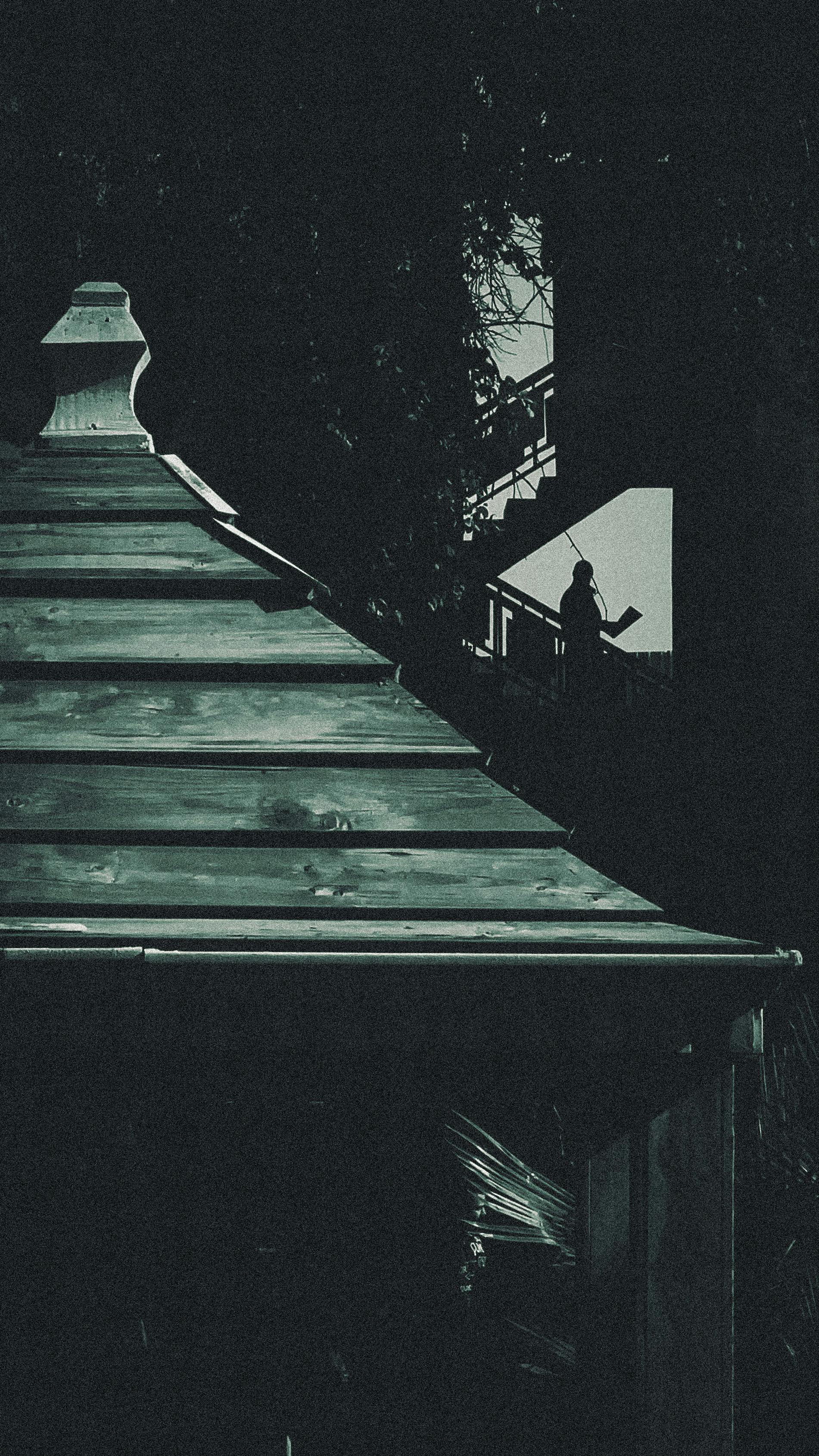 A dramatic silhouette stands near a shadowy shed, highlighting intrigue under the night sky.