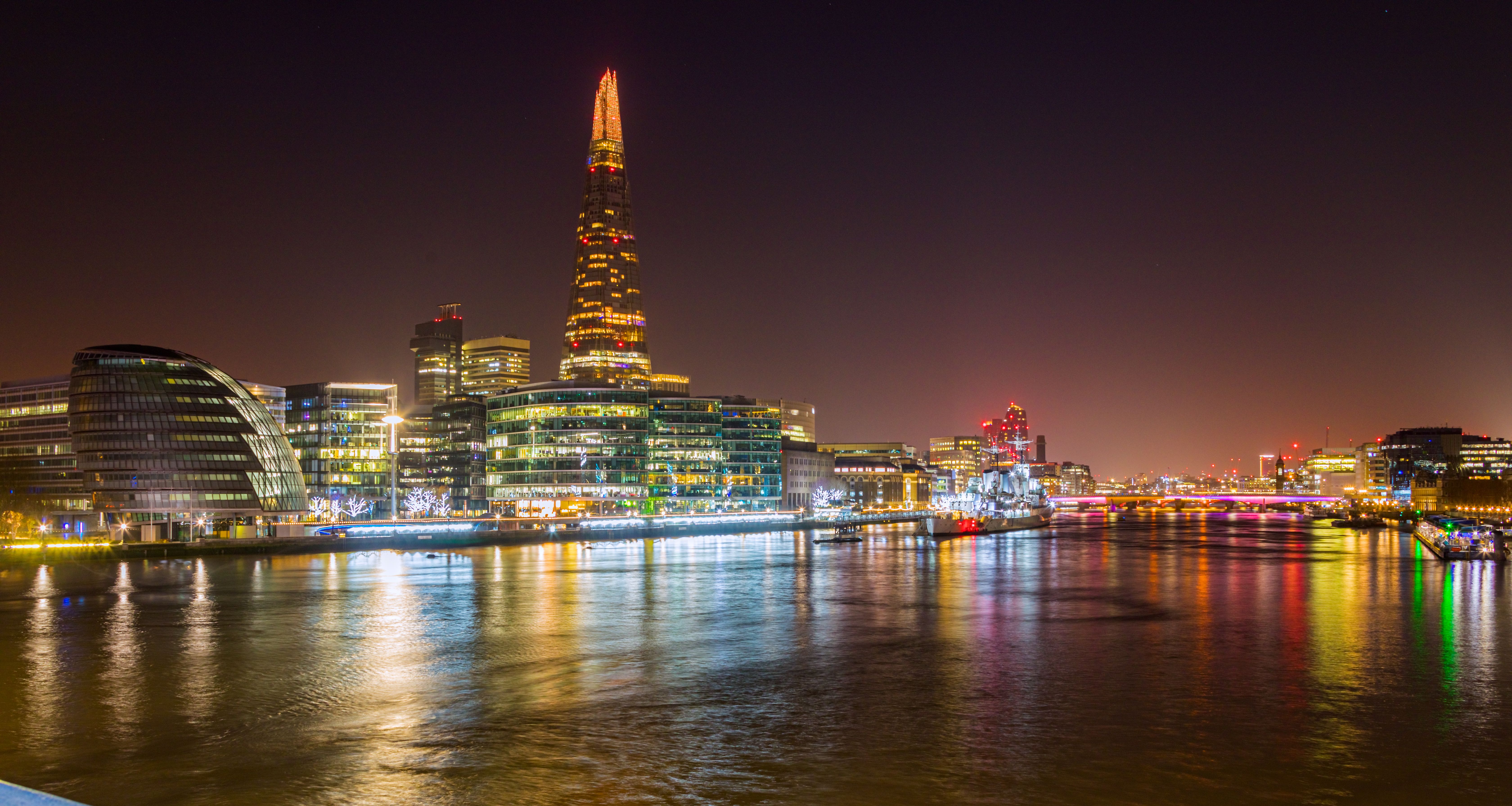 Scenic night view of London's cityscape featuring The Shard reflected on the Thames.