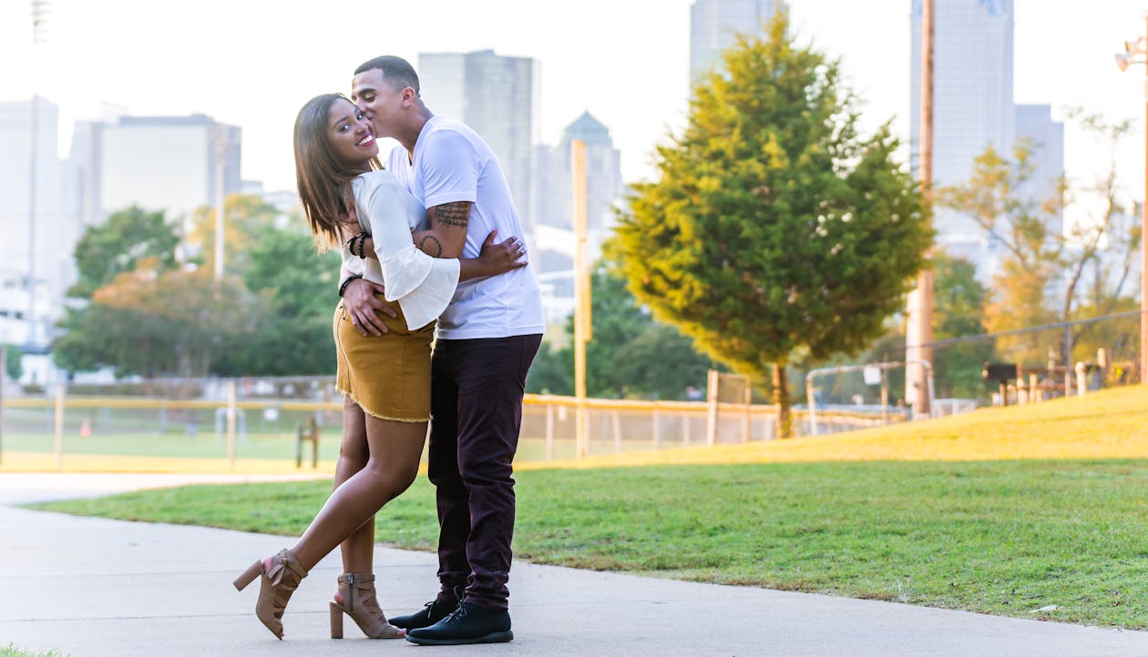 Man Kissing Woman Near Grass Field