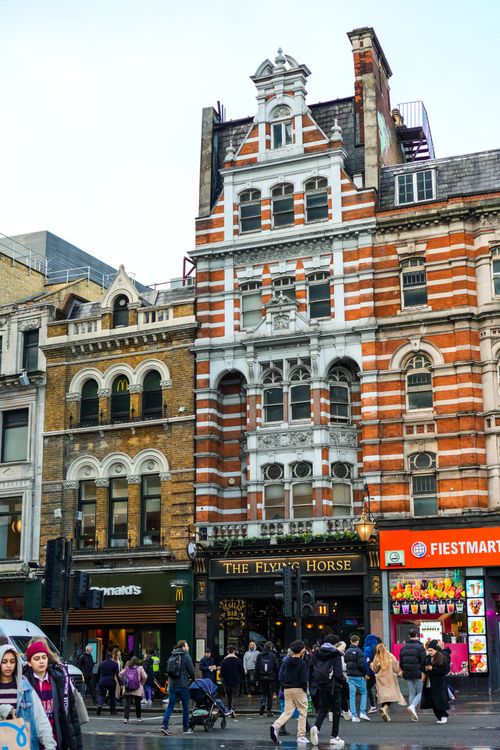Free A lively urban street with historic brick buildings and bustling pedestrians, showcasing city life. Stock Photo