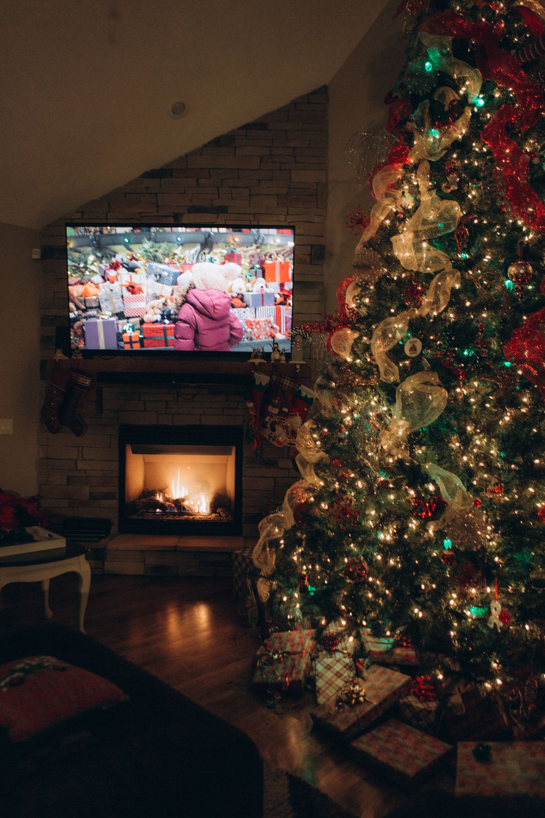 Christmas tree positioned beside a television and fireplace in a real family living room