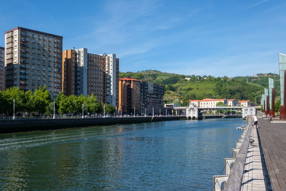 Paisaje urbano soleado de edificios modernos que bordean un canal en un entorno costero urbano.