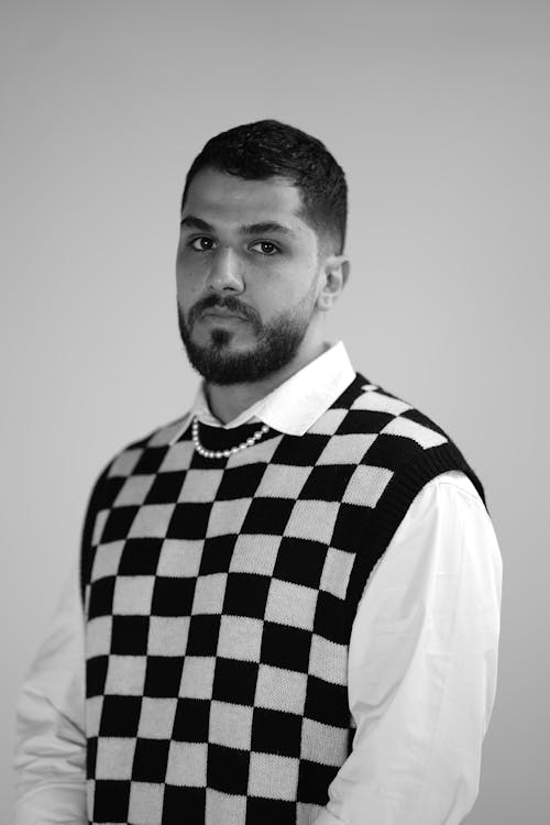 Grayscale Photo of a Man Wearing a Checkered Knitted Vest