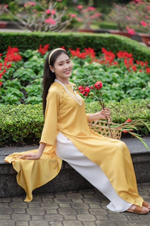 Free Woman in Yellow Ao Dai Holding a Flower Stock Photo