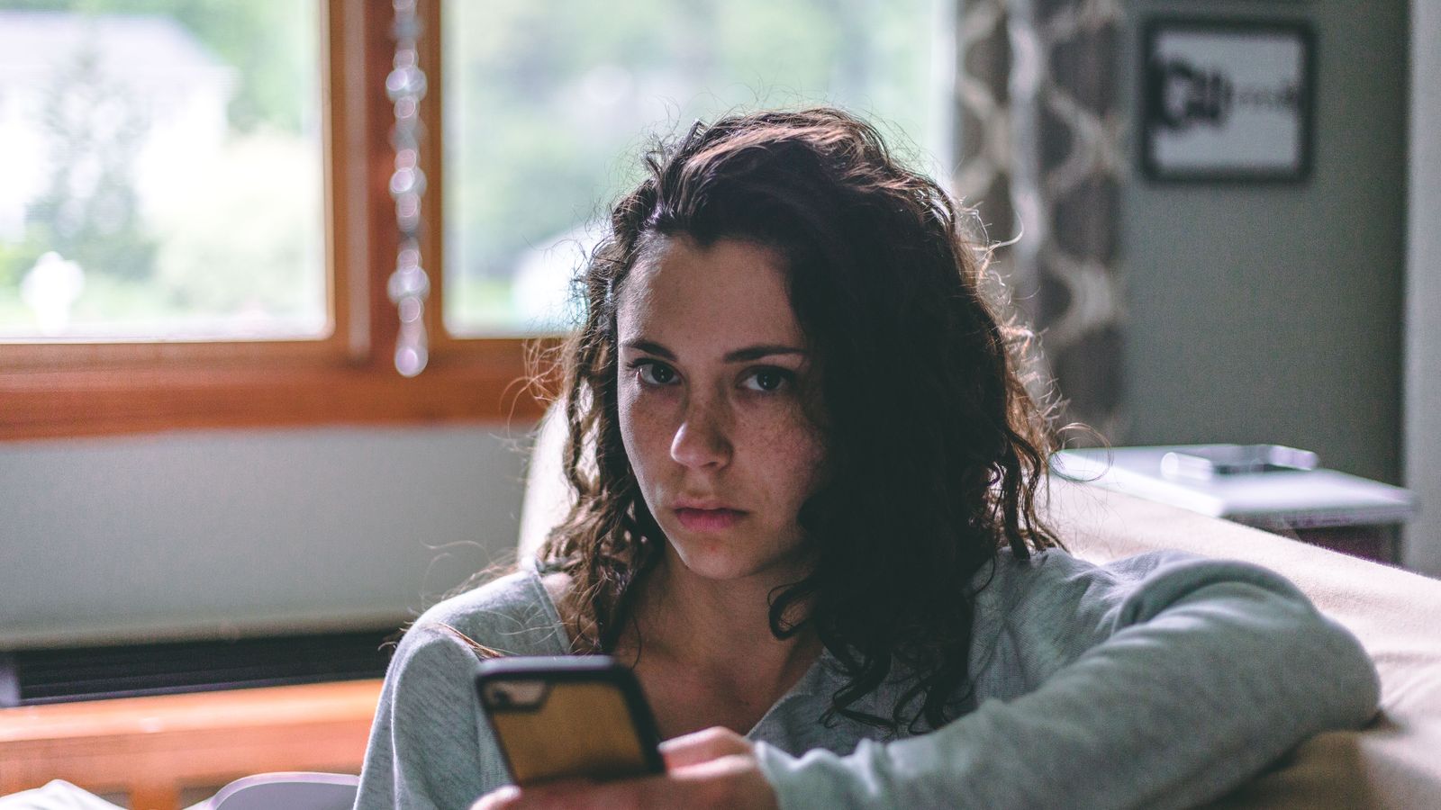 Mom relaxing on the couch with a phone showing income notifications