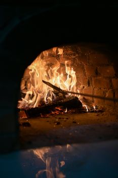 Close-up of a rustic brick oven with flames and a shovel inside, capturing a warm and fiery ambiance.