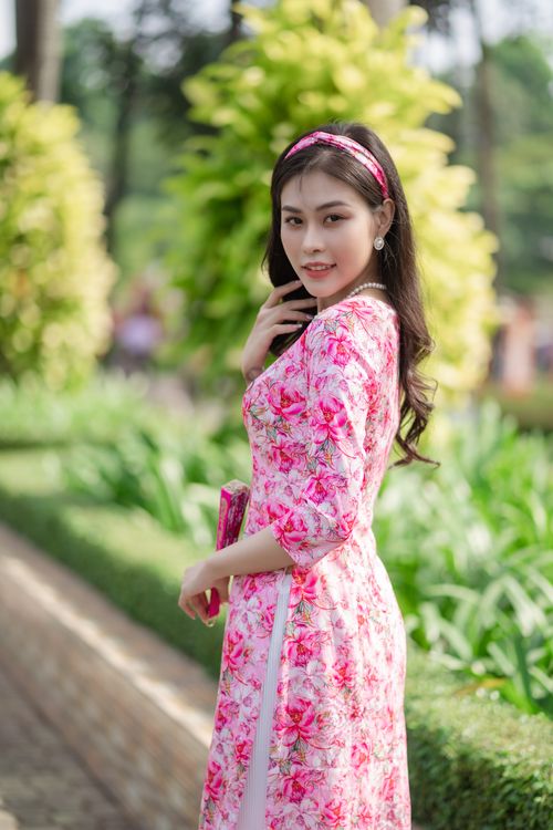 Free Beautiful young woman in a vibrant floral dress posing in a lush garden setting. Stock Photo