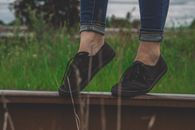 Person Wearing Black Low-top Sneakers Standing on Railing