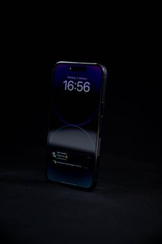 Close-up of a smartphone showcasing time and notifications against a dark background.
