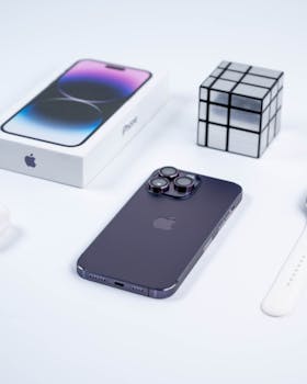 Close-up of a smartphone with tech gadgets and cube on a white background.