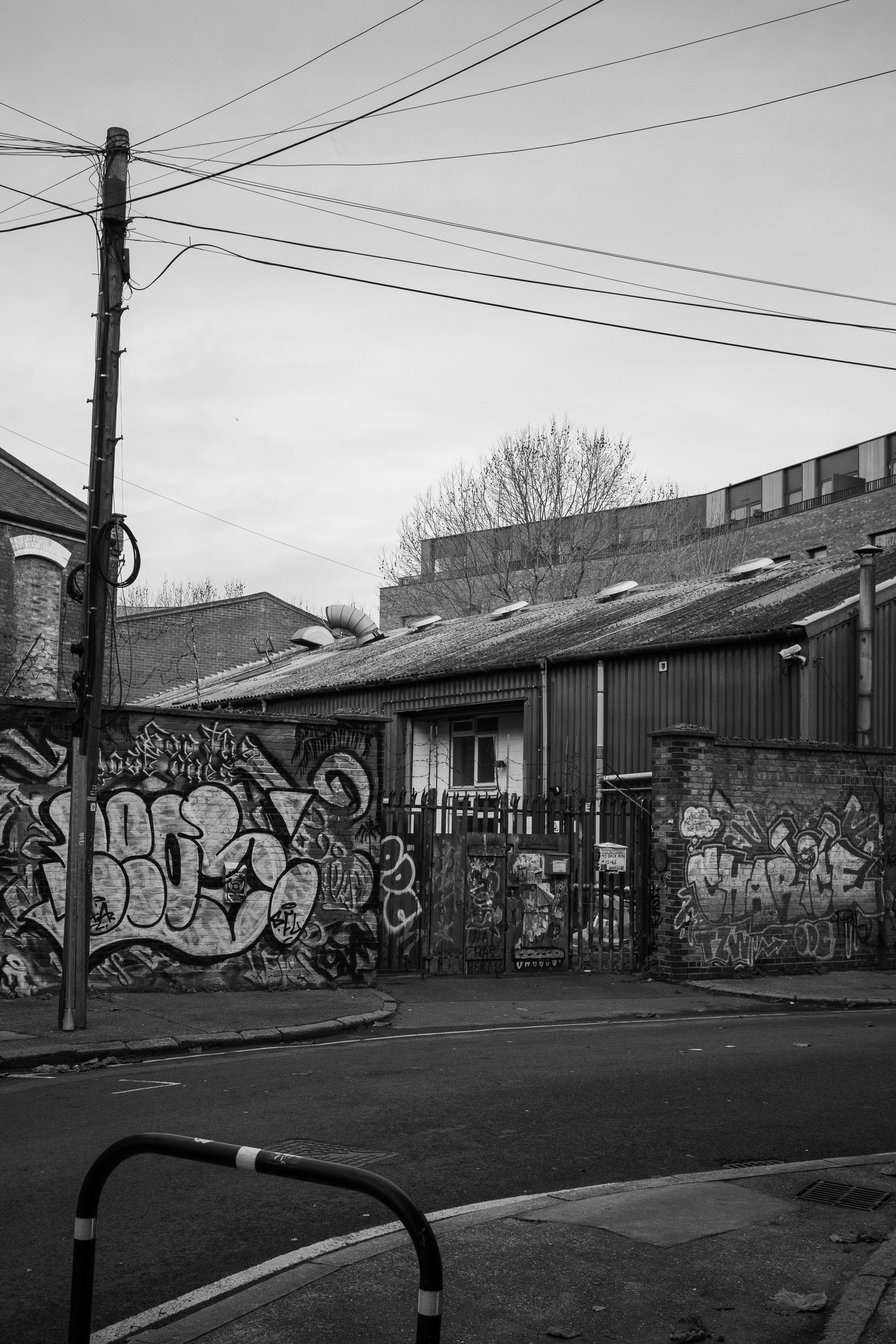 Free Grayscale street view of graffiti-covered walls in London's gritty urban landscape. Stock Photo