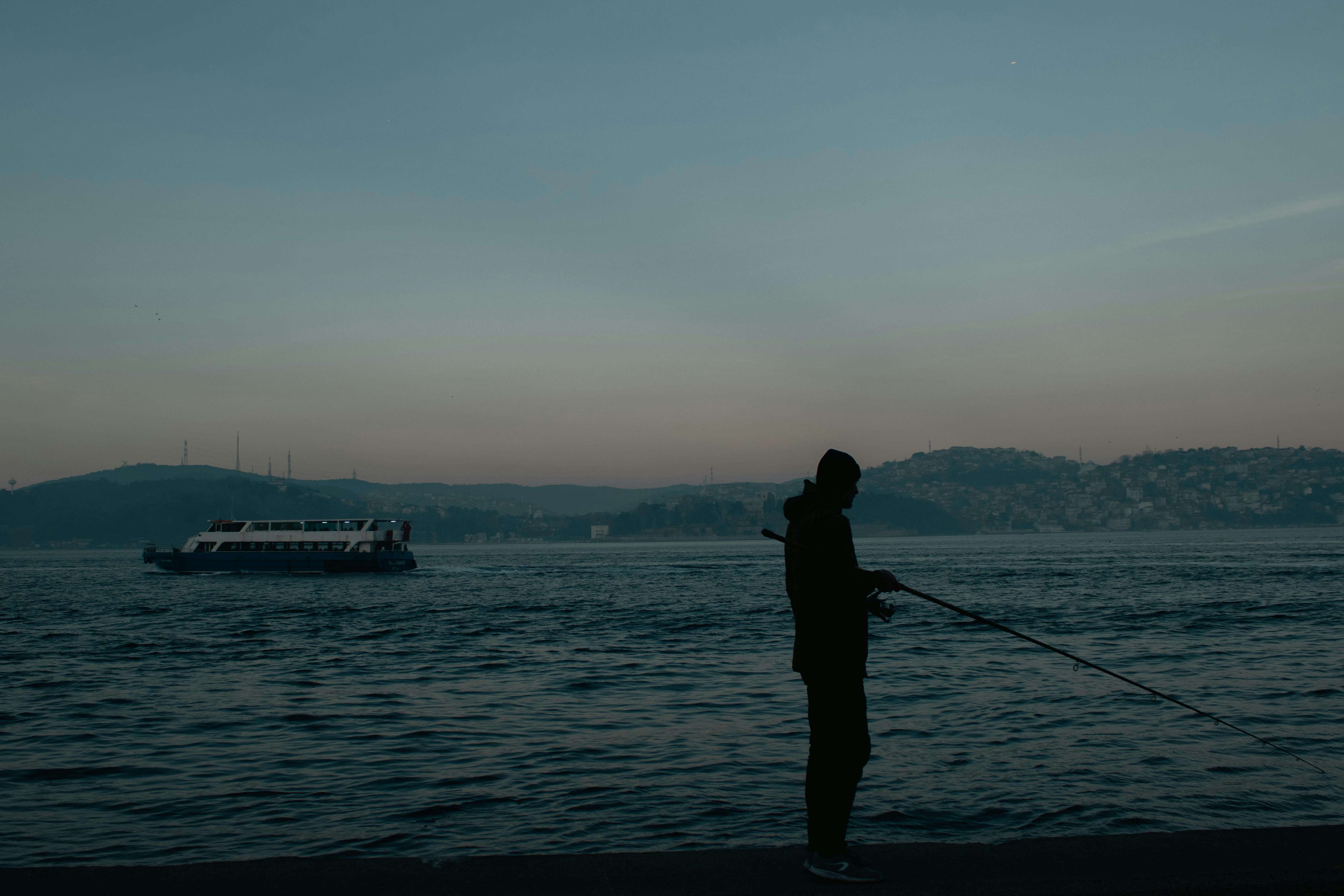 Silhouette of a Fisherman on the Shore · Free Stock Photo