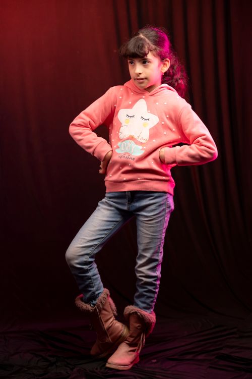 Free Charming young girl in jeans and a pink hoodie posing confidently, showcasing her playful style. Stock Photo