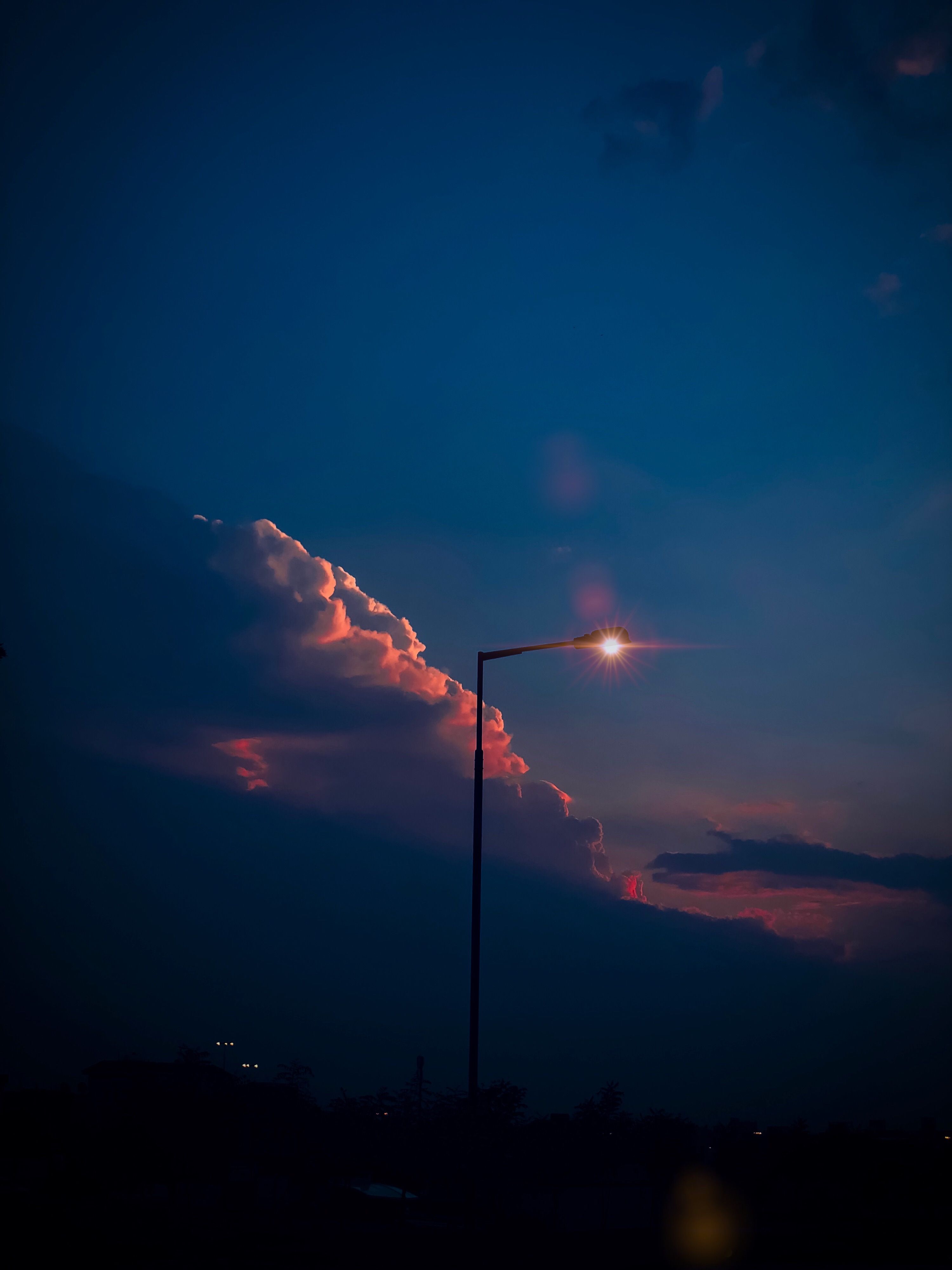 Silhouette of a street lamp against a colorful evening sky in Hamad Town, Bahrain.