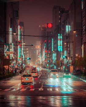 A captivating scene of Tokyo's urban landscape illuminated at night under rainy conditions, showcasing the city's vibrant energy.