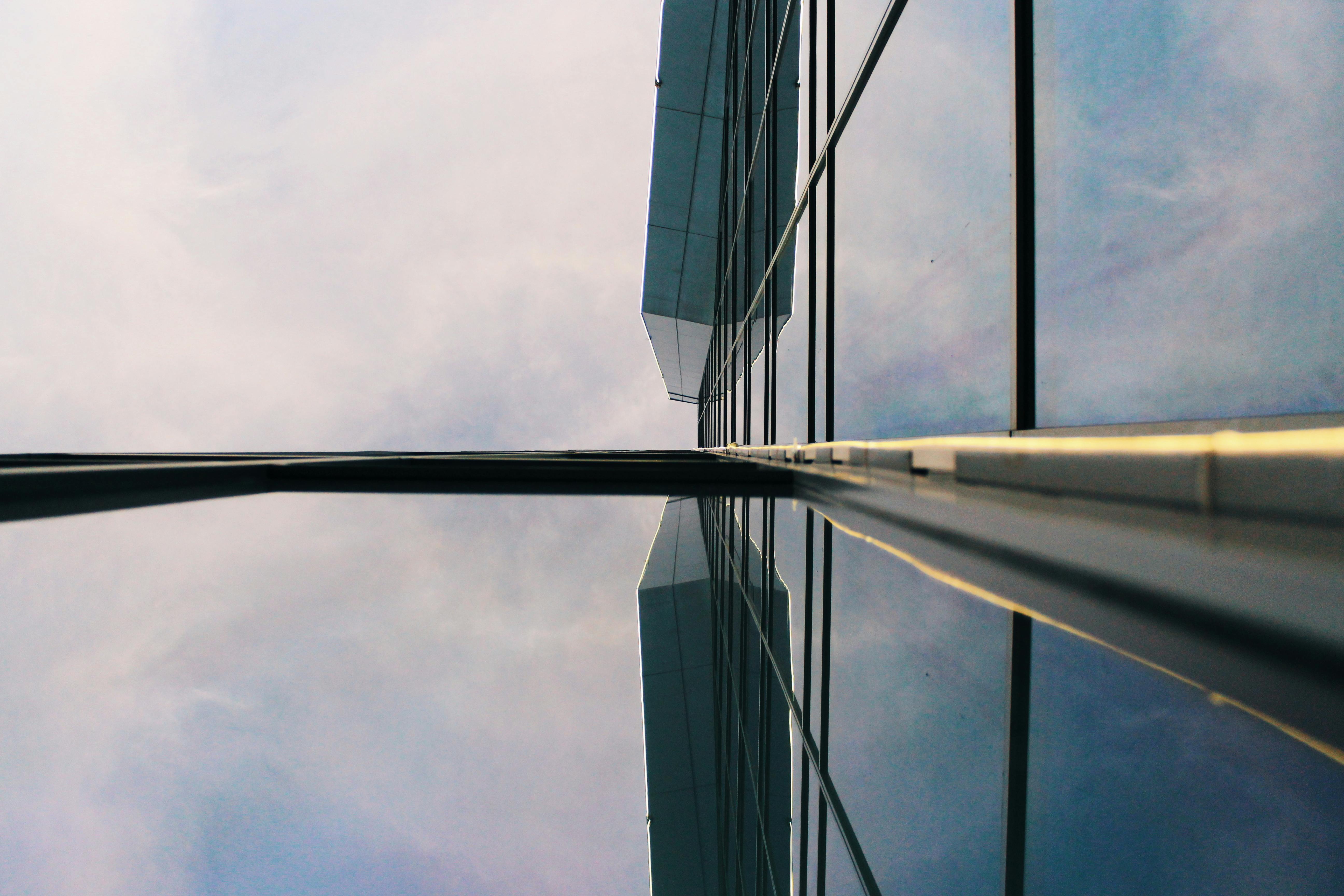 低角度拍摄的现代玻璃建筑映照着天空，展现了城市环境中的当代建筑设计