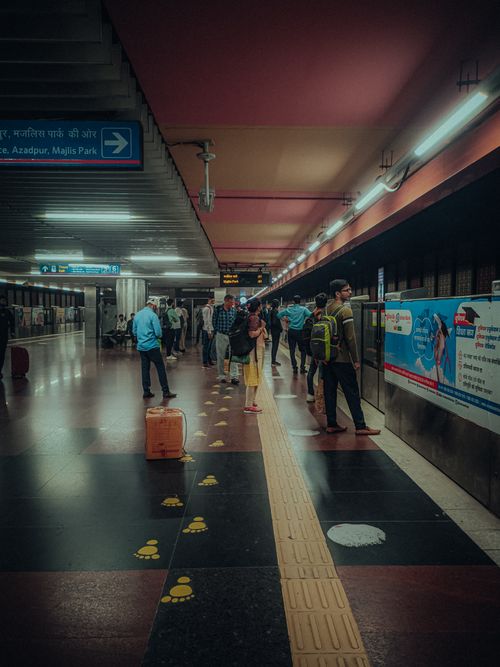 Free Commuters waiting on a platform at a New Delhi metro station, showcasing urban transit life. Stock Photo
