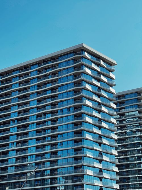 Free Contemporary high-rise buildings with glass facades under a bright blue sky. Stock Photo