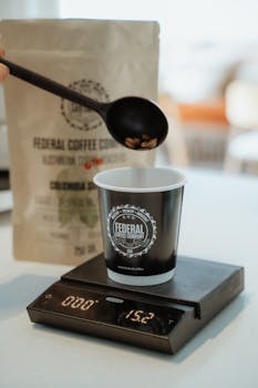 Coffee beans being carefully measured into a cup using a digital scale, focusing on precise brewing.