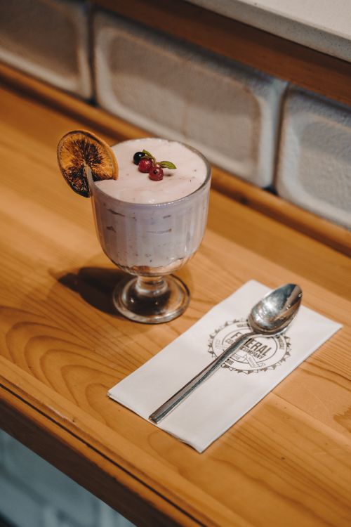 Free Creamy dessert garnished with berries and dried orange slice on a wooden surface with a spoon and napkin. Stock Photo