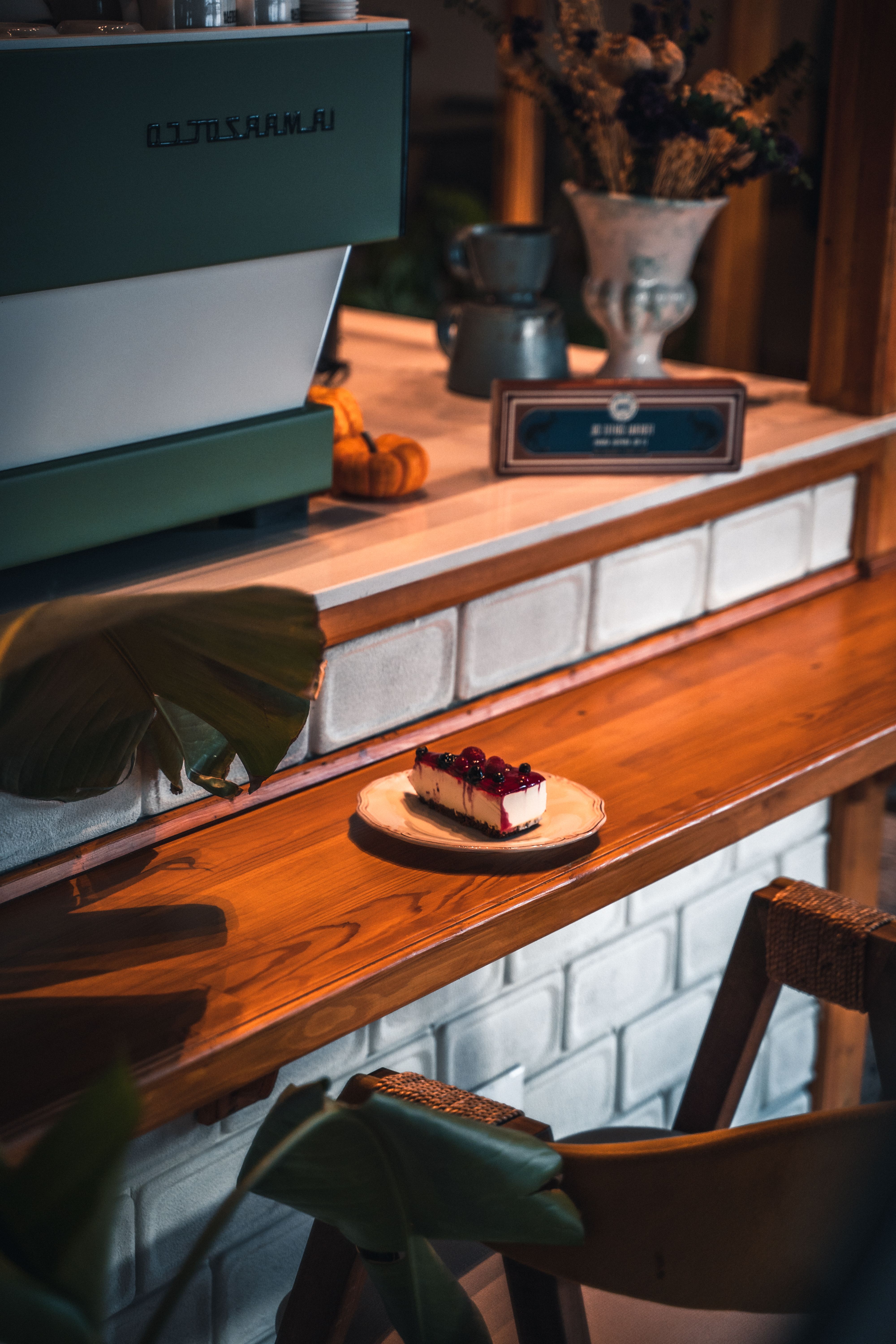 A cozy coffee shop setting with a piece of cheesecake on a wooden table, perfect for bakery or cafe vibes.