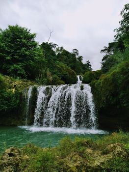 A serene waterfall cascading amidst vibrant green foliage, representing the beauty of nature.