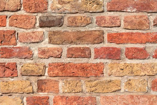 Detailed image of a rough, multicolored brick wall texture for backgrounds or design.