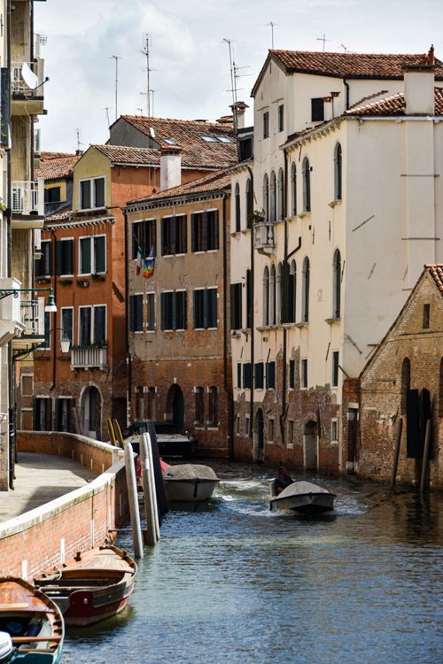 Free Charming view of a Venetian canal flanked by historic buildings and motorboats. Stock Photo