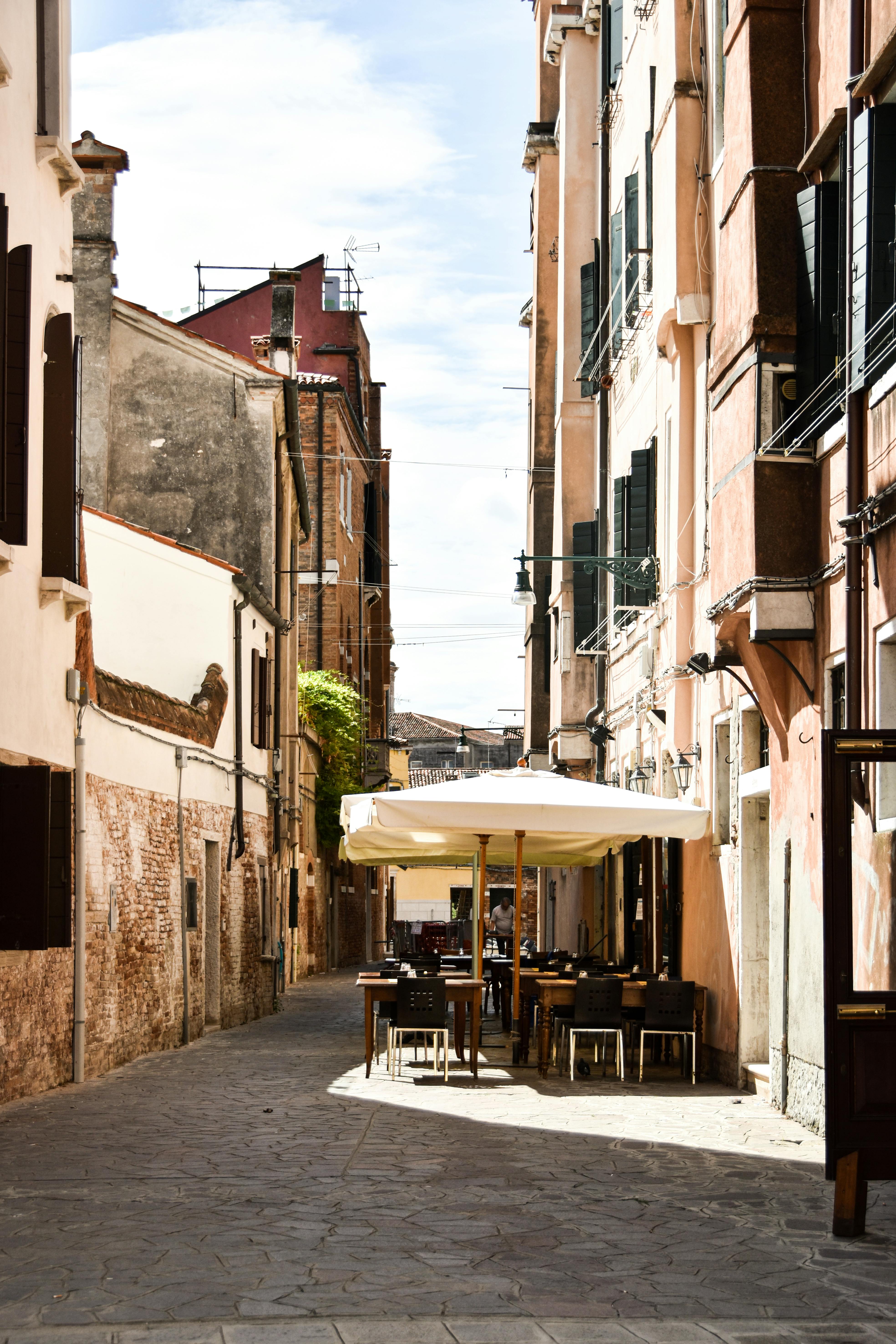 Explore a quaint outdoor cafe set in a charming European narrow street with unique architecture.