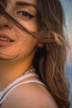 A captivating close-up of a woman smiling with her hair blowing in the wind outdoors.