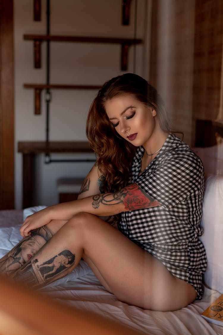 Tattooed Woman Sitting On Bed