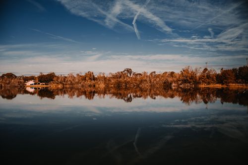 Free Peaceful autumn lake scene with clear blue sky and vibrant reflections. Stock Photo