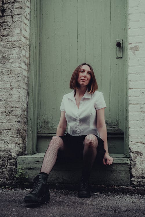 Woman in a Fashionable Outfit Sitting in front of the Door 