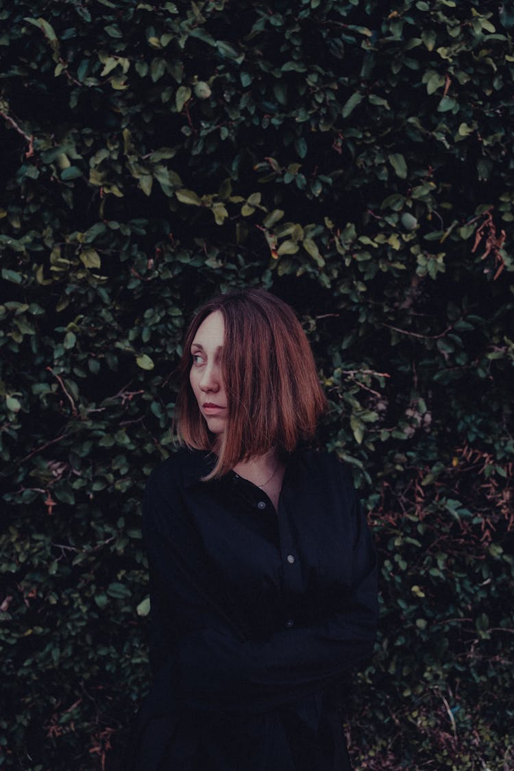 Portrait Of Woman In Black Shirt Among Green Hedge