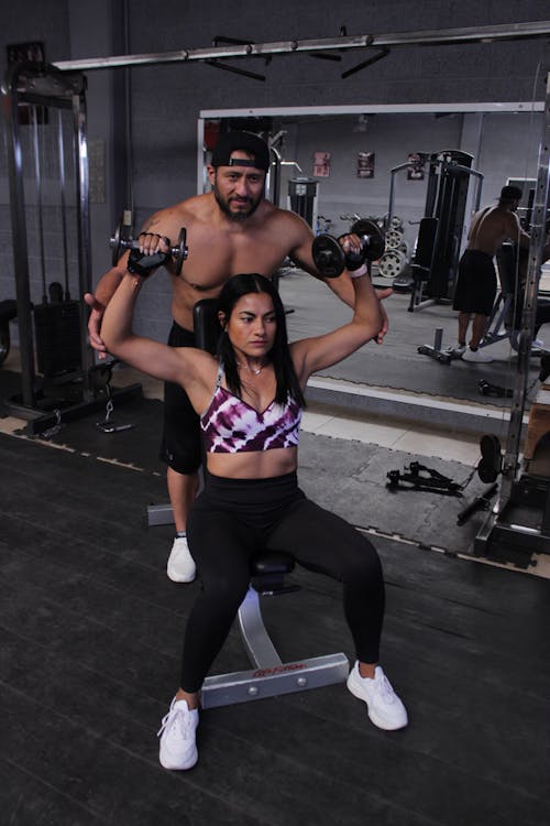 A Man Spotting a Woman doing a Shoulder Press