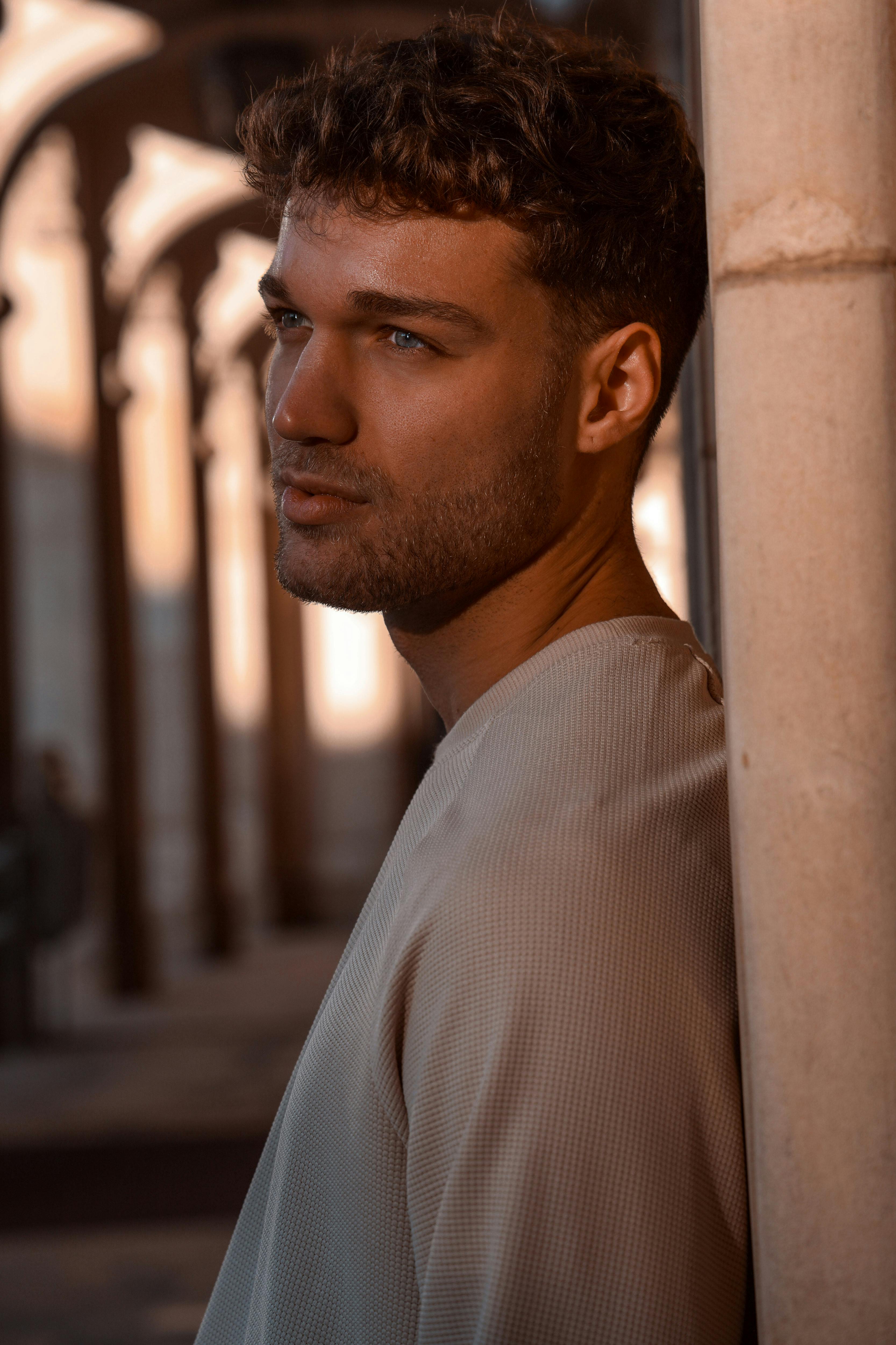 a man with curly hair leaning against a wall