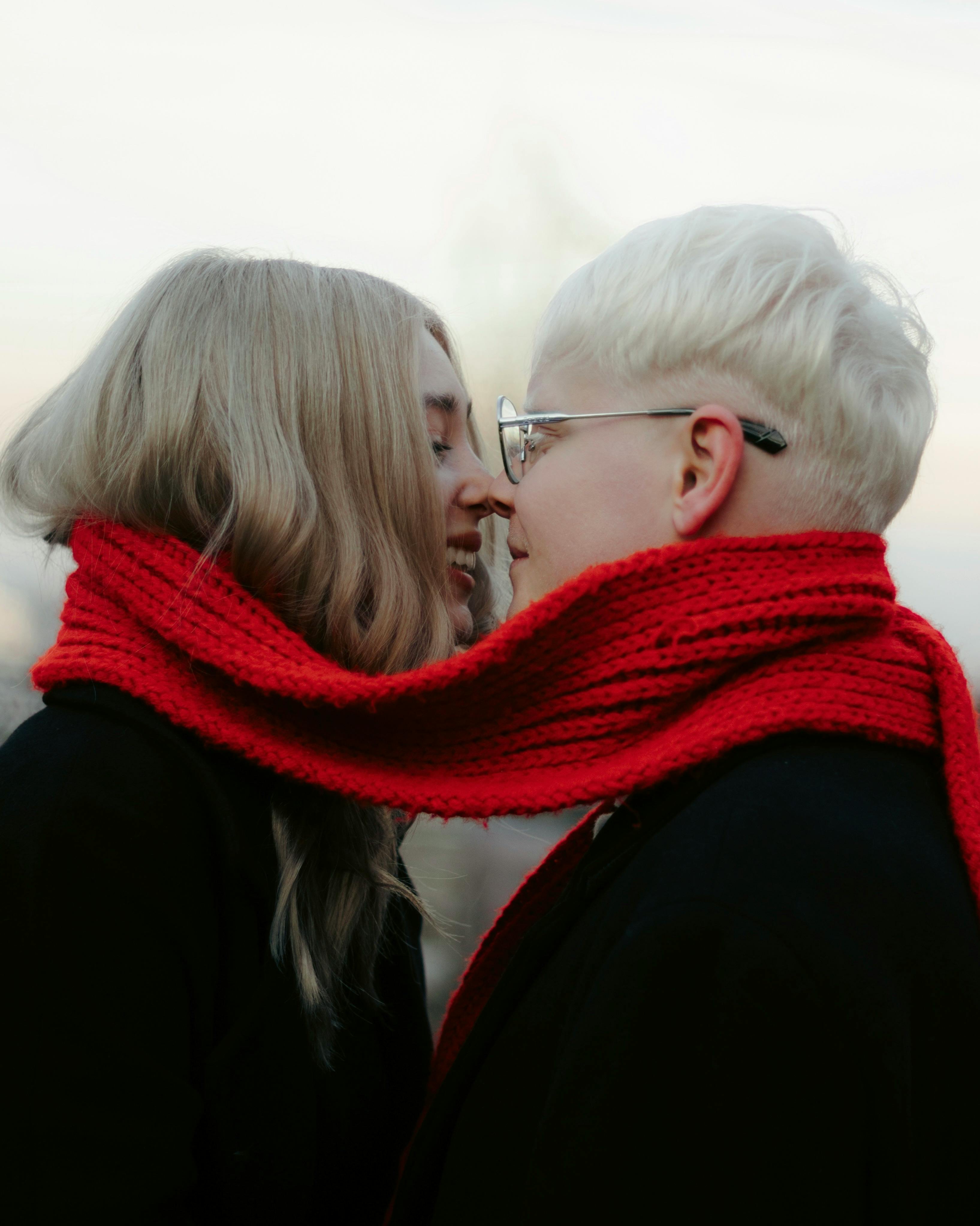 Couple wearing a red scarf, sharing an intimate moment outdoors during winter.