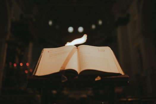 An open book under candlelight inside a majestic Milan cathedral, capturing a serene spiritual ambiance.