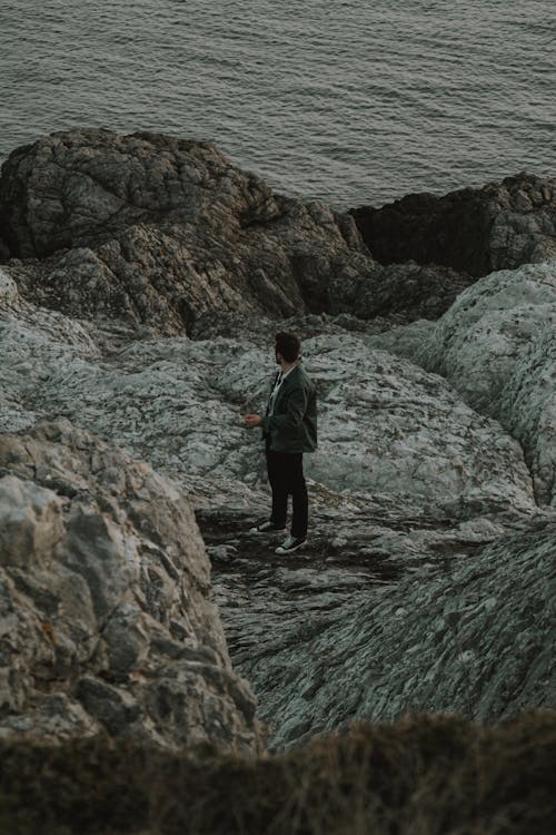 Man Standing on Rocks on Sea Shore
