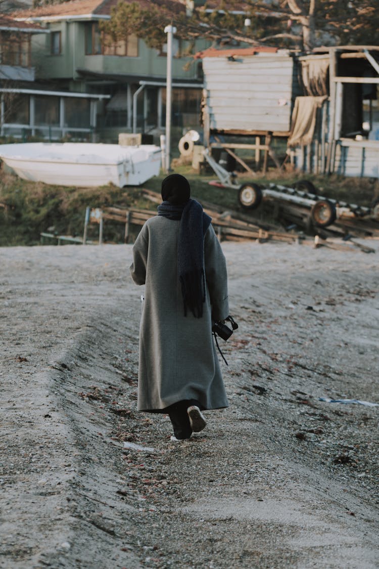 Woman Walking On The Beach In Coat