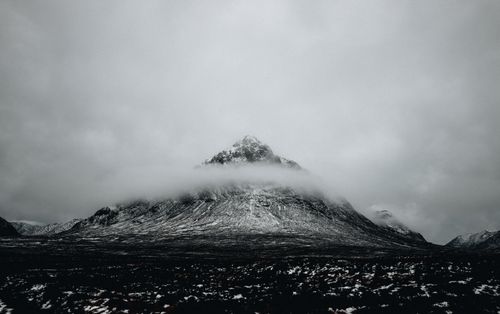 Free An awe-inspiring snowy mountain peak enveloped by clouds under an overcast sky. Stock Photo