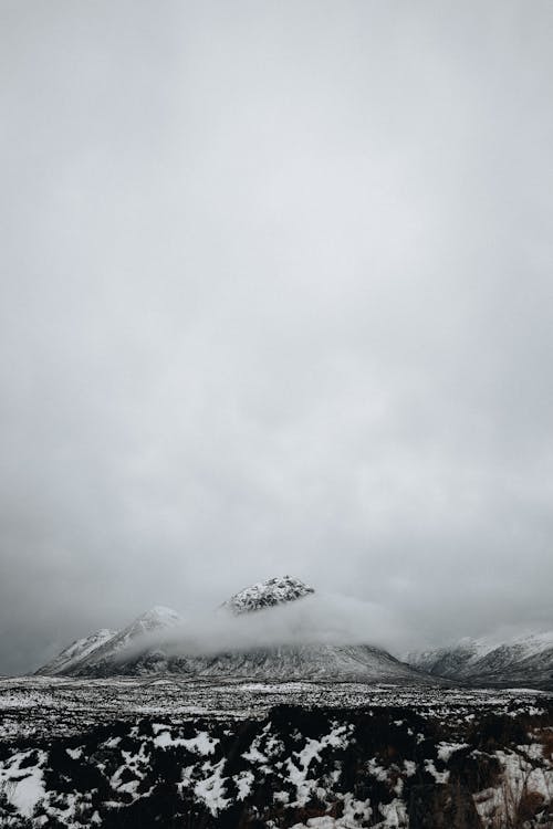 Grayscale Photo of Snow-Covered Mountains under the Sky